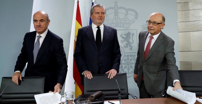 El portavoz del Gobierno, Íñigo Méndez de Vigo (c), junto a los ministros de Economía, Luis de Guindos (i), y de Hacienda, Cristóbal Montoro (d), al inicio de la rueda de prensa posterior a la reunión del Consejo de Ministros en el Palacio de La Moncloa.