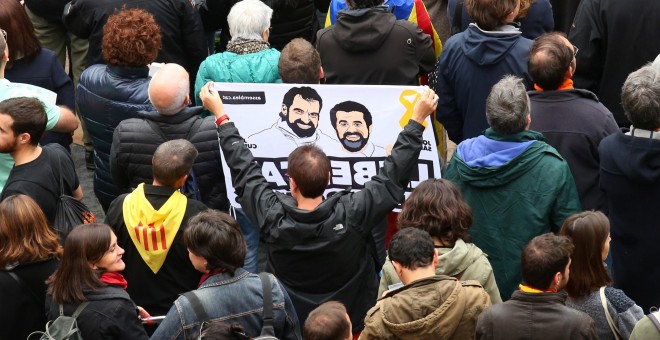 Un manifestante con una pancarta reclamando la puesta en libertad de los presidentes de ANC y Omnium Cutural, Jordi Sanchez y Jordi Cuixart, respectivamente, en la concentración en la Plaza de Sant Jaume durante la jornada de huelga general en Catalunya.