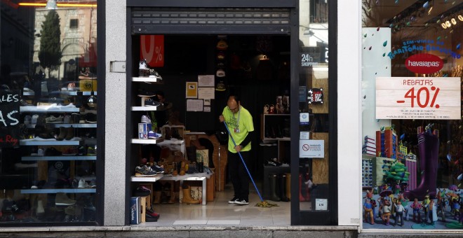 Un empleado de una tienda en el centro de Madrid limpia la entrada del establecimiento. REUTERS