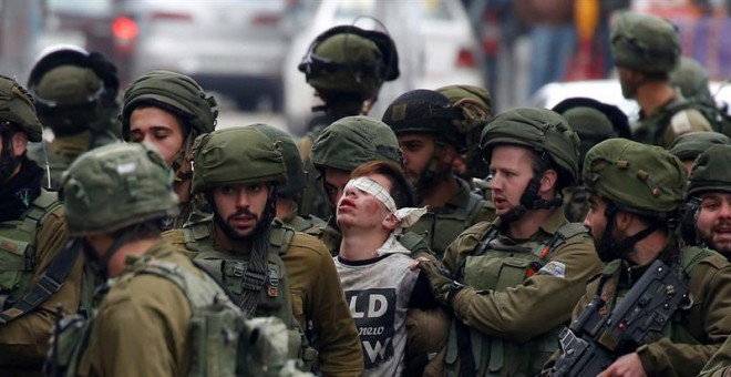 Soldados israelíes detienen a un manifestante durante unas protestas contra la decisión del presidente estadounidense, Donald Trump, de reconocer a Jerusalén como capital de Israel, en la ciudad cisjordana de Hebrón (Palestina).- EFE/ Abed Al Hashlamoun
