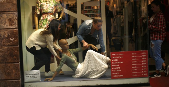 Un par de empleados arreglan el escaparate de una tienda en el centro de Madrid. REUTERS