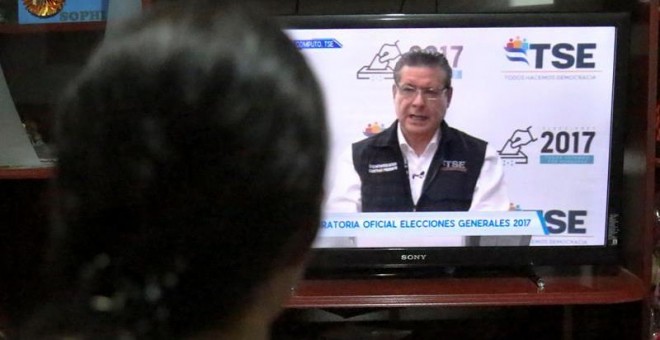 Un mujer escucha un discurso del magistrado presidente del Tribunal Supremo Electoral (TSE) David Matamoros, a través de un canal nacional de televisión en Tegucigalpa (Honduras). EFE/Gustavo Amador