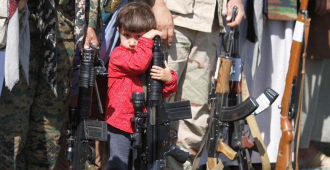Un niño descansa apoyado sobre un arma en Yemen./REUTERS