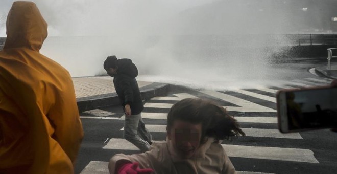 Varias personas son sorprendidas por una ola en el Paseo Nuevo de San Sebastián, durante el paso del temporal de invierno Bruno, que ha dejado rachas muy fuertes de viento y ha provocado olas de hasta siete metros. EFE/Javier Etxezarreta.