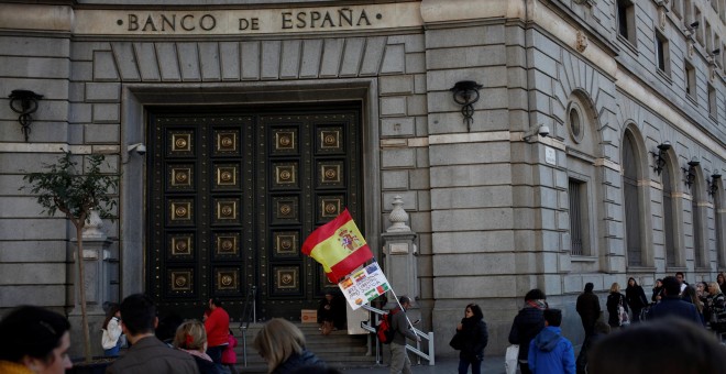 Un hombre con la bandera española y una pancarta junto a la sede del Banco de España en Barcelona. REUTERS/Jon Nazca