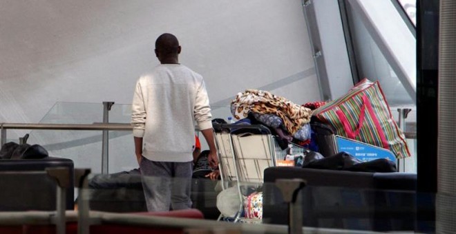 Uno de los zimbabuenses varados en el aeropuerto de Bangkok desde el pasado 23 de octubre, de espaldas en la terminal de salidas en el aeropuerto Suvarnabhumi de Bangkok.- EFE