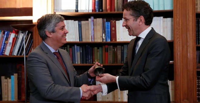 El holandés Jeroen Dijsselbloem, estrecha la mano del portugués Mario Centeno, ministro portugués de Finanzas,  y le hace entrega de la campanilla con la que abre las reuniones del Eurogrupo, en la ceremonia de traspaso de poderes, celebrada en la embajad