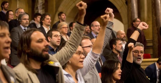 El diputado de la CUP Carles Riera (d) acompañado de los demás miembros de la formación cantan 'Els Segadors', puño en alto, al finalizar el pleno de constitución que ha dado inicio a la XII legislatura. EFE/Quique García