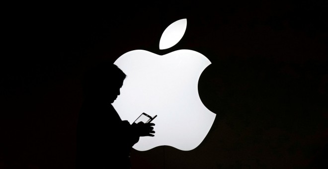 Una mujer mira el móvil enfrente de un logo de Apple en una tienda de la compañía situada en Shanghai, China. REUTERS/Aly Song/Archivo