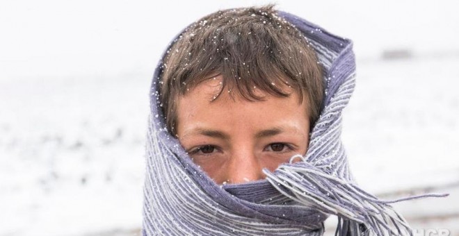 Un joven refugiado sirio se cubre para protegerse del frío en el valle de la Bekaa, en el Líbano, en enero de 2016.-  ACNUR/UNHCR/Haidar Darwish.