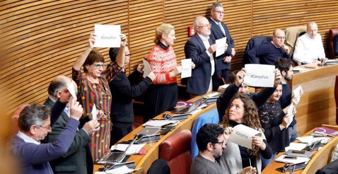 Los diputados de Podemos muestran carteles con el lema '#Campsfora' en el pleno de Les Corts Valencianes tras la votación de la propuesta de Compromís para instar a Camps a renunciar como miembro del Consell Jurídic Consultiu y al resto de prerrogativas q