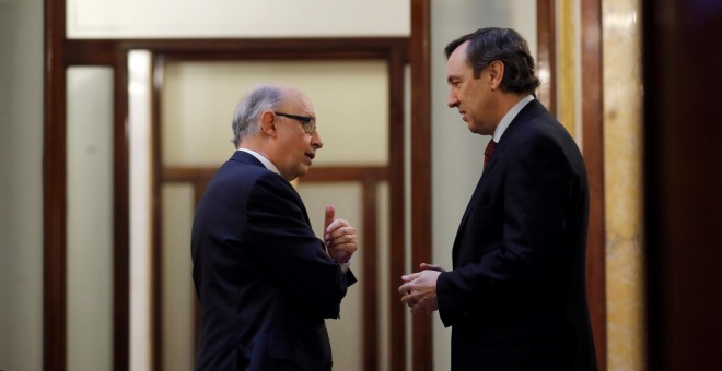 El ministro de Hacienda, Cristobal Montoro, conversa con el portavoz parlamentario del PP, Rafael Hernando, en los pasillos del Congreso, momentos antes del inicio de la sesión de control al Gobierno en el Congreso de los Diputados. EFE/Juan Carlos Hidalg