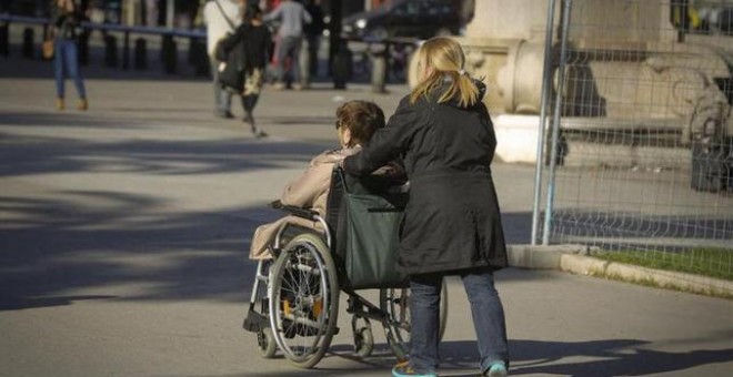 Una mujer mayor pasea con su cuidadora. EFE