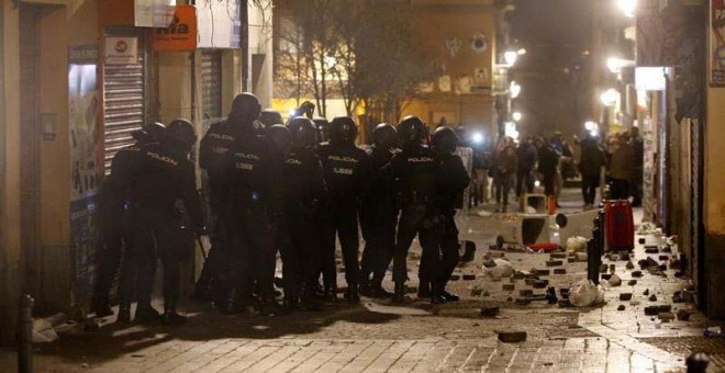 Policías antidisturbios en la calle Mesón de Paredes con la calle del Oso, en el barrio de Lavapiés de Madrid, repelen las protestas tras la muerte de un mantero de un paro cardíaco durante un control policial. | JAVIER LIZÓN (EFE)
