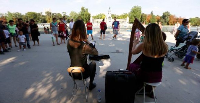 Dos jóvenes tocan junto al estanque del Retiro. EFE