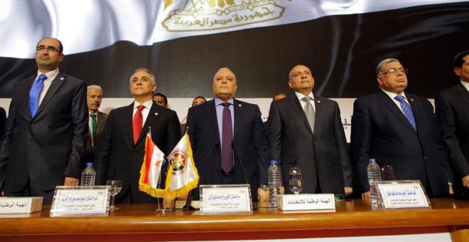 El jefe de la Comisión Nacional Electoral egipcio (NEC), Lasheen Ibrahim (c), y otros miembros no identificados, permanecen de pie antes de ofrecer una rueda de prensa en la que anuncian los resultados finales de las elecciones presidenciales, en El Cair
