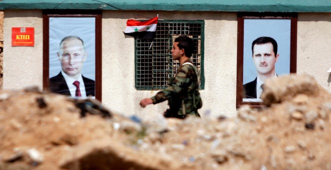 Un soldado sirio pasa junto a dos retratos de Bashar al Assad y Vladimir Putin en la ciudad de Guta. /REUTERS