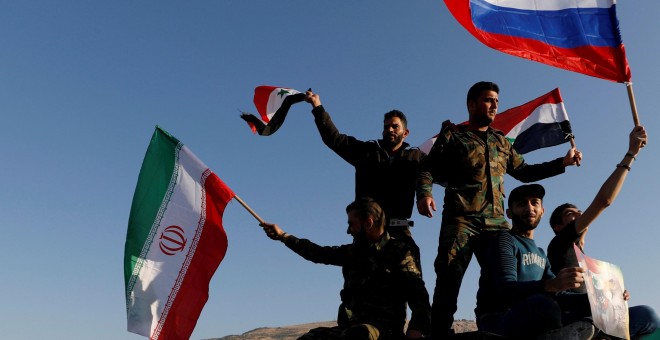 Sirios ondean las banderas de Irán, Rusia y Siria en protesta por los ataques en Damasco. /REUTERS