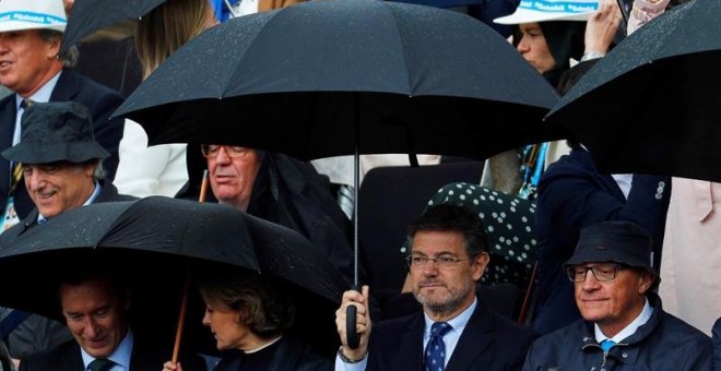 Rafael Catalá, con un paraguas para protegerse de la lluvia en la final del Open BancSabadell-Trofeo Conde de Godó. EFE/Alejandro García