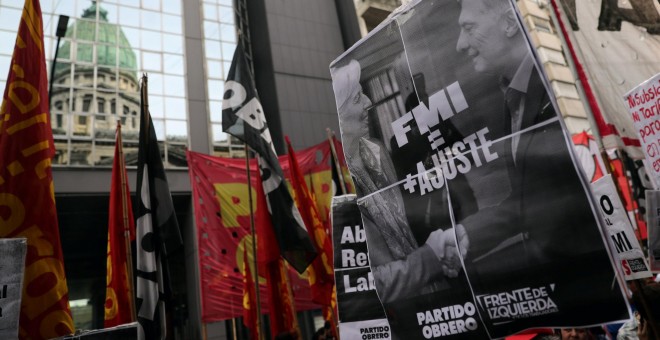 Un manifestante sostiene una pancarta con la imagen del la directora gerente del FMI, Christine Lagarde, y del presidente argentino, Mauricio Macri, en una protesta frente al Congreso, en Buenos Aires. REUTERS/Marcos Brindicci