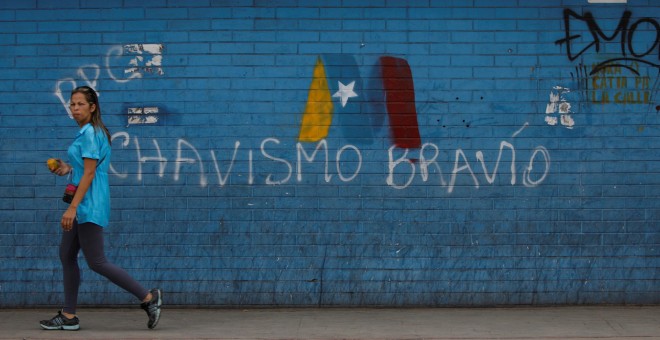 Una mujer pasa junto a un graffiti en Caracas en apoyo a Nicolas Maduro en las elecciones presidenciales. REUTERS/Adriana Loureiro