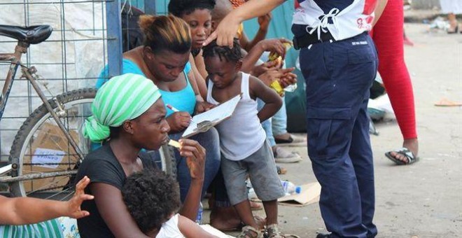 Mujeres y niños reposan en una frontera - EFE