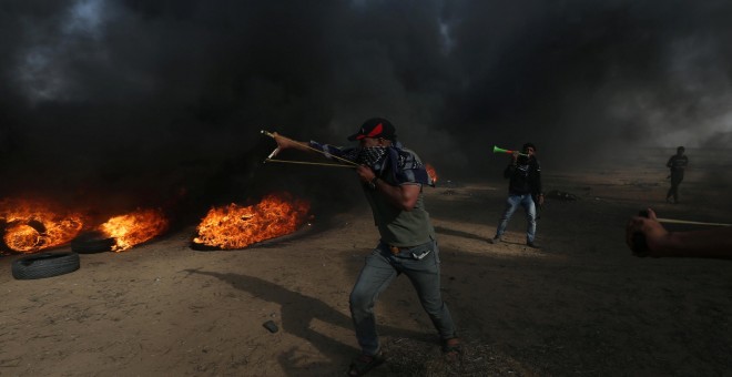 Un manifestante usa un tirachinas para arrojar piedras durante una protesta en la que los palestinos reclaman el derecho a regresar a su patria, en la frontera entre Israel y Gaza. REUTERS / Ibraheem Abu Mustafa