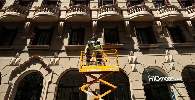 Unos trabajadores sobre una plataforma colocan una luz en una farola en Barcelona. REUTERS/Albert Gea