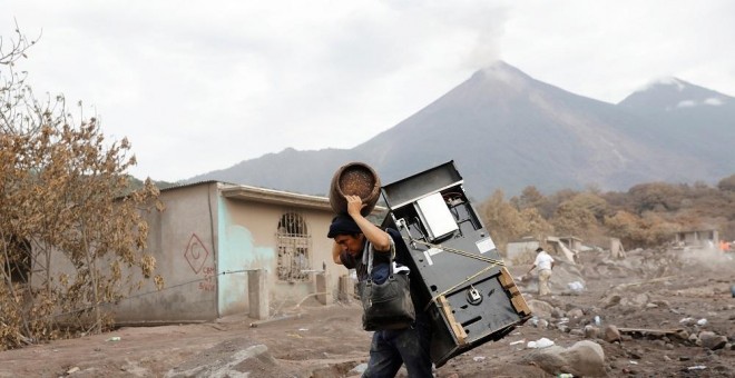 Un hombre recupera algunos objetos de su casa afectada por la erupción del Volcán de Fuego./REUTERS