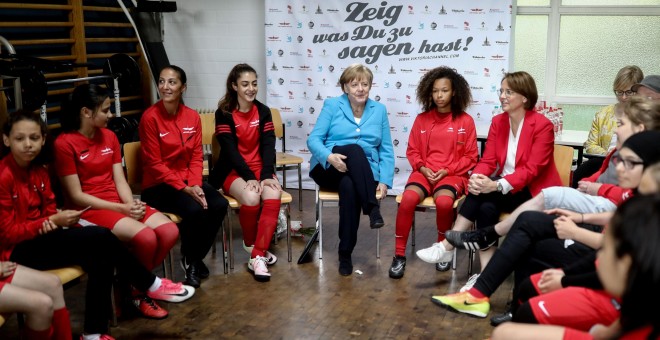 La canciller alemana Angela Merkel y la secretaria de Estado Annette Widmann-Mauz conversan con las jugadoras del SV Rot-Weiss Viktoria Mitte 08 como parte del evento 'Deportes e integración' en Berlín. REUTERS/Kay Nietfeld