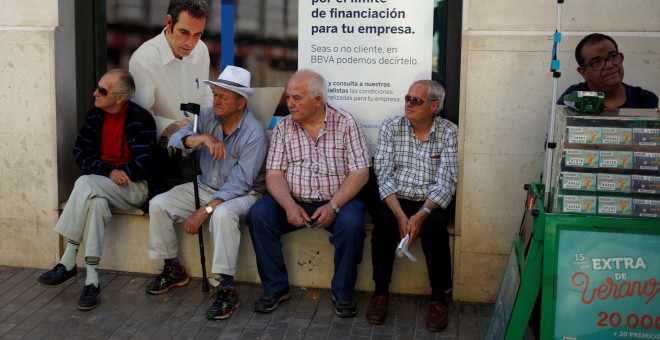 Varios pensionistas sentados en la ventada de una sucursal del BBVA en el cenro de Málaga.. REUTERS/Jon Nazca