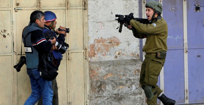 Un soldado israelí apunta con su arma a unos fotógrafos durante enfrentamientos con manifestantes palestinos en una protesta en la ciudad cisjordana de Hebrón. / REUTERS