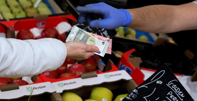 Una cliente paga la compra en un puesto de fruta en un mercado de Madrid. REUTERS/Sergio Perez