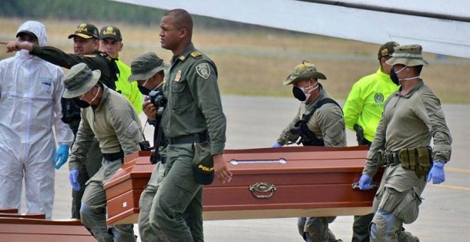 Personal de la Policía ayuda hoy, viernes 22 de junio de 2018, en Cali (Colombia), a cargar los ataúdes con los cuatro cuerpos hallados por las autoridades colombianas en una zona selvática. (ERNESTO GUZMÁN Jr. | EFE)