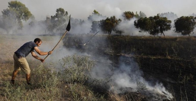 Un hombre apaga un incendio en Kibbutz de Kissufim, a lo largo de la frontera con la Franja de Gaza,  provocado por material inflamable adherido a un globo de helio. / AFP - MENAHEM KAHANA