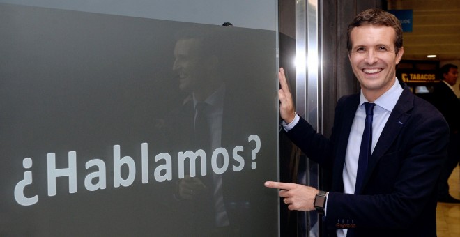 El candidato a la Presidencia del PP Pablo Casado posa junto una publicidad de un establecimiento comercial, en el que se puede leer “¿Hablamos?”. EFE/Nacho Gallego