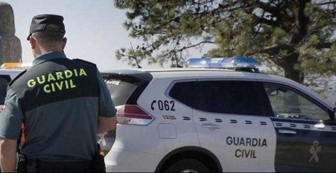 Agente de la Guardia Civil junto a un coche patrulla. GUARDIA CIVIL