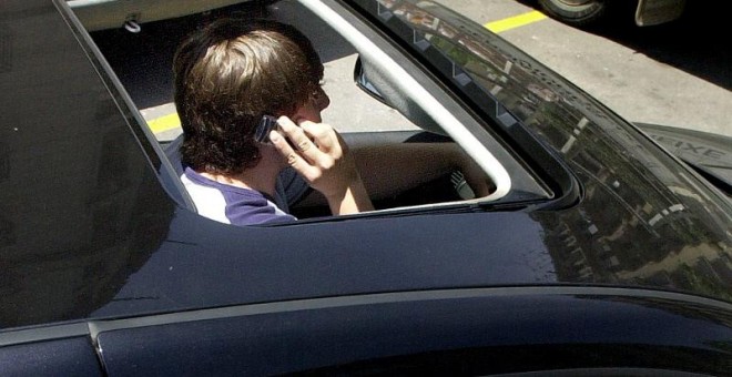 Foto de archivo de dos personas hablando por el móvil dentro de un coche. - EFE