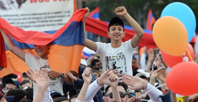 Dos jóvenes armenios portando una bandera durante una concentración en Yereván, Armenia. / Reuters