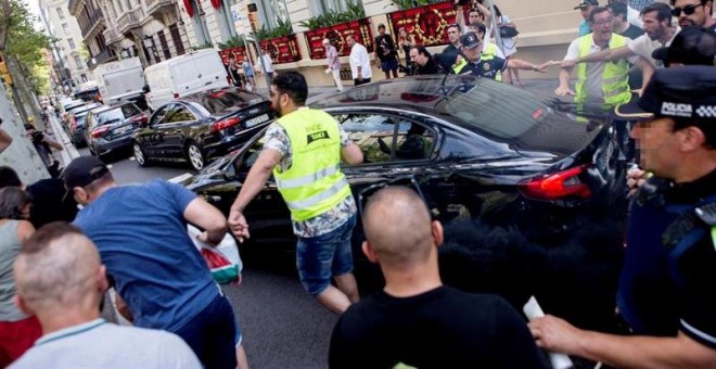 25/07/2018.- Taxistas increpan a un coche frante al hotel Palace durante la manifestación por las calles de Barcelona motivo de la huelga en defensa del reglamento del AMB que limita las licencias de VTC. EFE/Quique García