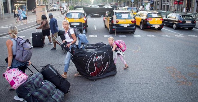 31/07/2018.- Unos turistas llevan sus maletas mientras los taxistas mantienen las concentraciones en el centro de la ciudad con motivo de la huelga iniciada el pasado 25 de julio, por el conflicto de las licencias VTC (alquiler de vehículos con conductor)