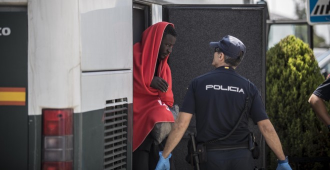 Un migrante baja del autobús de la Guardia Civil que le han trasladado del un pabellón cercano hasta el nuevo centros de atención para extranjeros habilitado en el puerto de Campamento (Cádiz).- JAIRO VARGAS