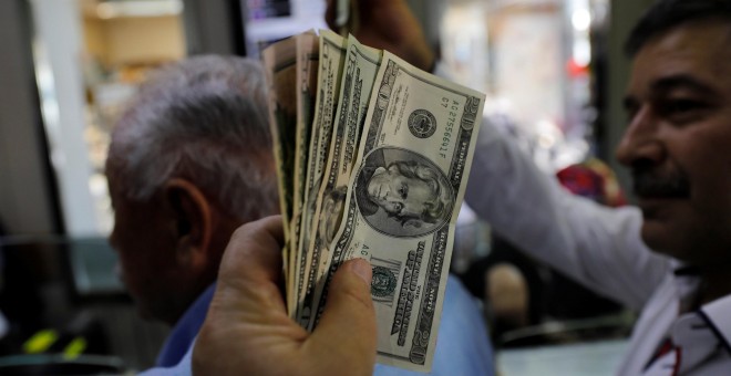 Un hombre sostiene un fajo de billetes de dólar en una oficina de cambio de moneda en Ankara. REUTERS/Umit Bektas