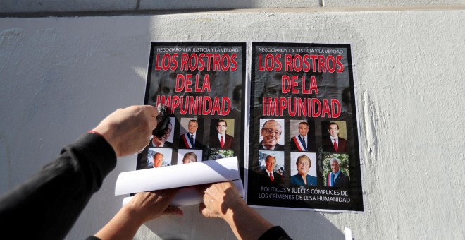 Chilenos pegan carteles en la pared con imágenes de los políticos del país que hacen llamar 'los rostros de la impunidad' - Reuters