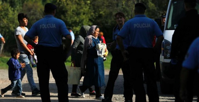Agentes de la Policía croata escolta na varios migrantes. - REUTERS