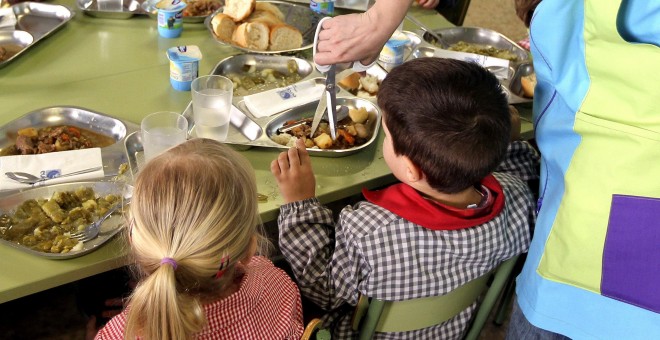 Una madre ayuda a dar de comer a los niños en un colegio público zaragozano. EFE/Javier Cebollada