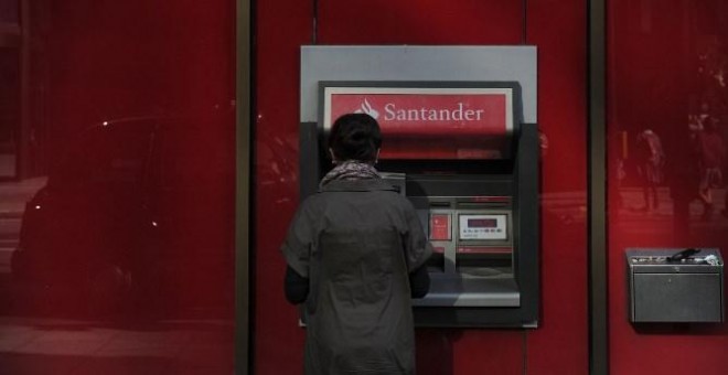 Una mujer utiliza un cajero automático en una oficina del Banco Santander en el centro de Londres. AFP/Carl Court