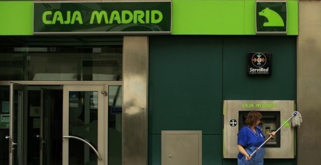 Una empleada limpia la facahda de una oficina de Caja Madrid en Sevilla. REUTERS/Marcelo del Pozo