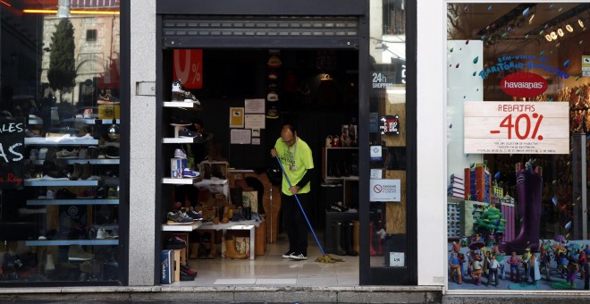 Un trabajador limpia la entrada de una tienda de zapatillas en Madrid. REUTERS/Susana Vera
