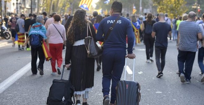 Dos turistas con sus maletas por una calle de Barcelona en la que marcha una manifestación independentista. AFP/Josep Lago